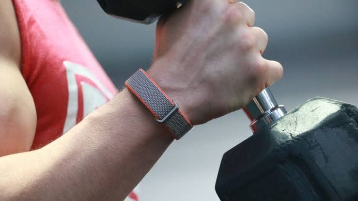 Bicep curl exercise performed by an arm wearing a Fitbit Air screenless fitness tracker.