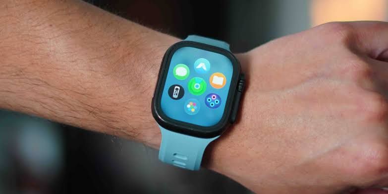 An Apple Watch Ultra equipped with a rugged titanium band resting on a charging stand.