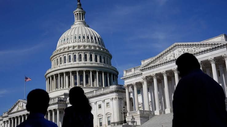Pedestrians walk past the U.S. Capitol building during an evaluation of federal hiring trends.