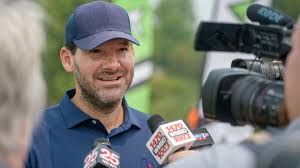 Former Dallas Cowboys quarterback Tony Romo standing on a football field during a broadcast segment.