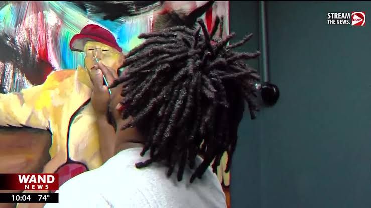 Artist Antonio Burton painting a mural on a wall in Decatur, Illinois.