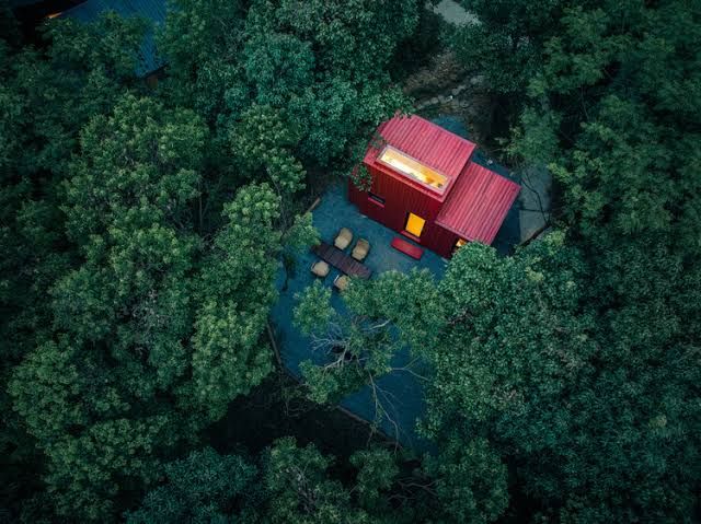 The Red Submarine Cabin, a compact wooden modular structure, sits in a forest clearing in 2026.