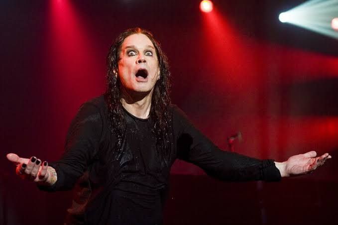 Ozzy Osbourne performing on stage with a microphone in his hand during a live concert event.