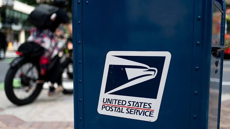 USPS mail sorting facility featuring stacks of letters and ballot envelopes in a sorting machine.