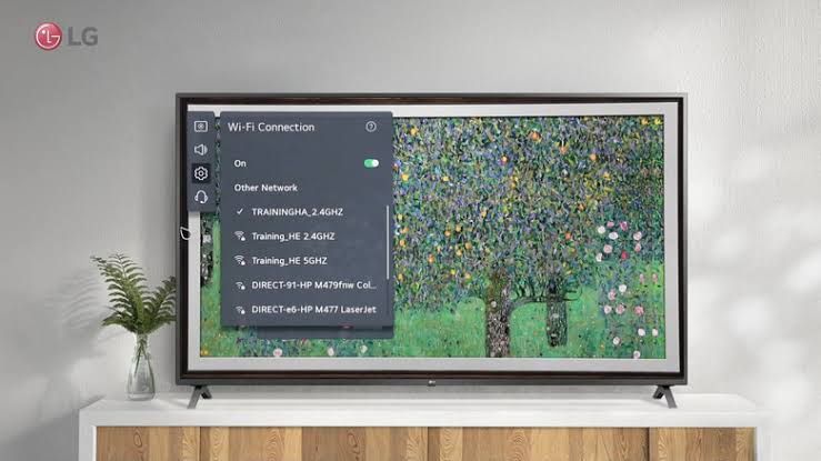 Close-up of an LG television remote control pointing toward a dark screen, illustrating network connectivity troubleshooting.