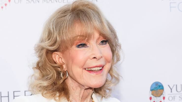 Barbara Eden smiling while attending a public event in a formal outfit.