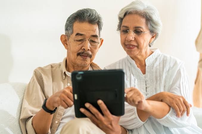 A person checking a personal finance document at a desk with a calculator and a social security statement nearby.