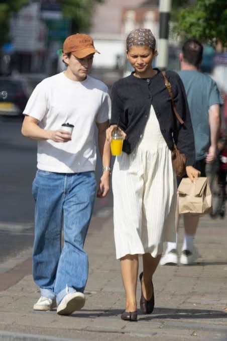 Zendaya and Tom Holland walking down a London street while grabbing coffee on a casual afternoon.