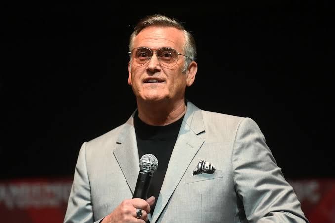 Bruce Campbell posing for a photograph during an appearance at a fan convention event.