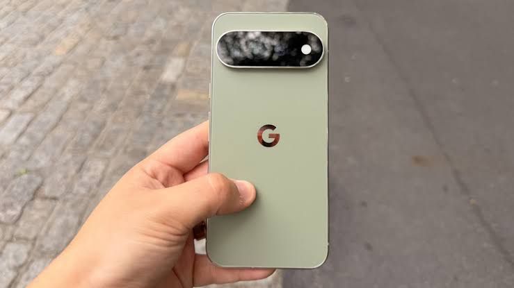 Pixel 11 Pro XL held in a hand against a blurred city backdrop, showing the redesigned camera bar.
