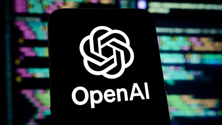 OpenAI logo on a smartphone screen with code displayed in the background.