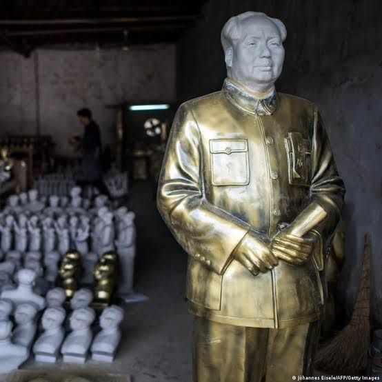 A sculptor works on multiple statues of Mao Zedong in a Chinese workshop.