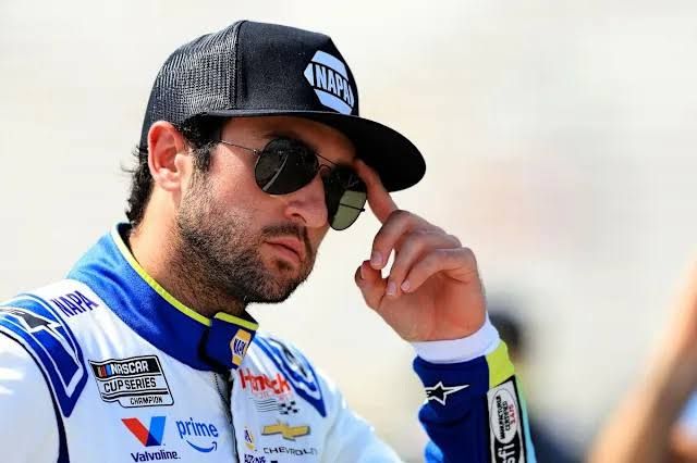 Chase Elliott standing near his race car at North Wilkesboro Speedway during a press conference.