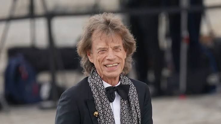 Ronnie Wood smiling while holding a guitar during a professional photoshoot.