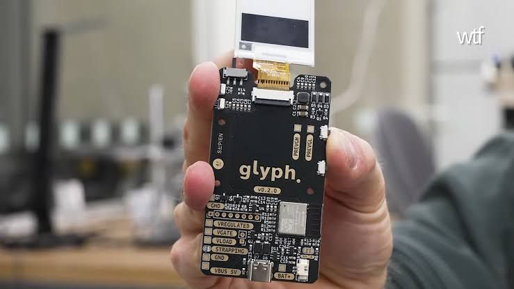 Glyph wallet with E Ink display showing a QR code next to XR glasses on a table.