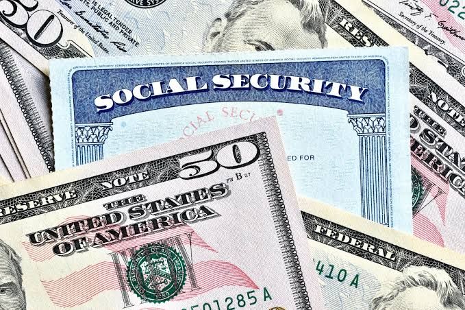 Social Security card resting on top of a stack of U.S. dollar bills.