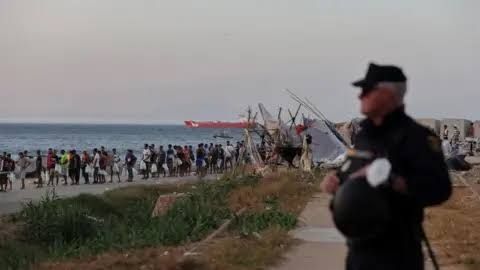 Migrants wait for Red Cross food at Trampolin beach following the mass crossing into the Spanish exclave of Ceuta.