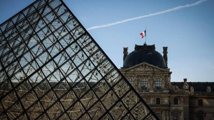 The French flag flies over the Louvre museum facade in Paris during a 2026 security review.