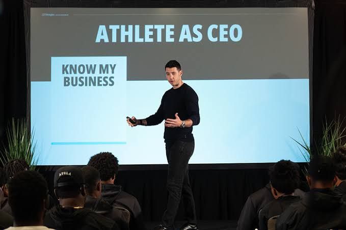Mikael Lemieux, a JPMorgan wealth advisor, speaking to college athletes in a locker room setting.