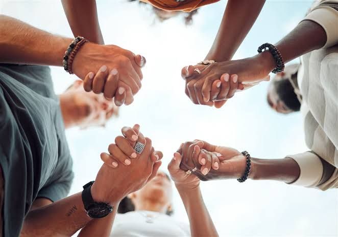 People holding hands in a circle as a sign of prayer and support for spiritual and mental growth.