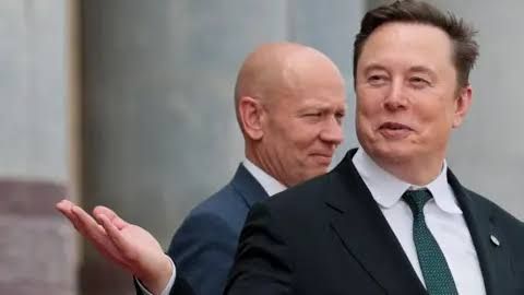 Elon Musk gestures while wearing a suit and tie during an appearance in China.