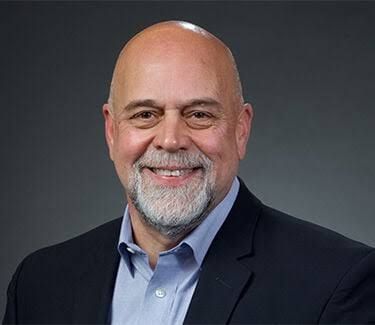 Mac Edwards stands in a studio setting, reflecting his 35-year career in radio management and broadcasting.