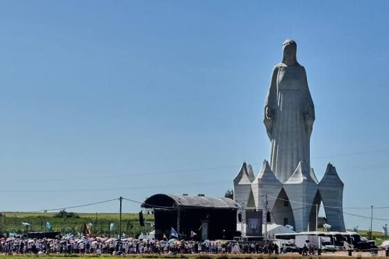 A towering white statue of the Virgin Mary stands above a crowd in the Polish village of Konotopie.