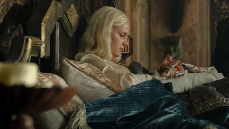 Helaena Targaryen sitting in her quarters stitching with a somber expression in House of the Dragon.