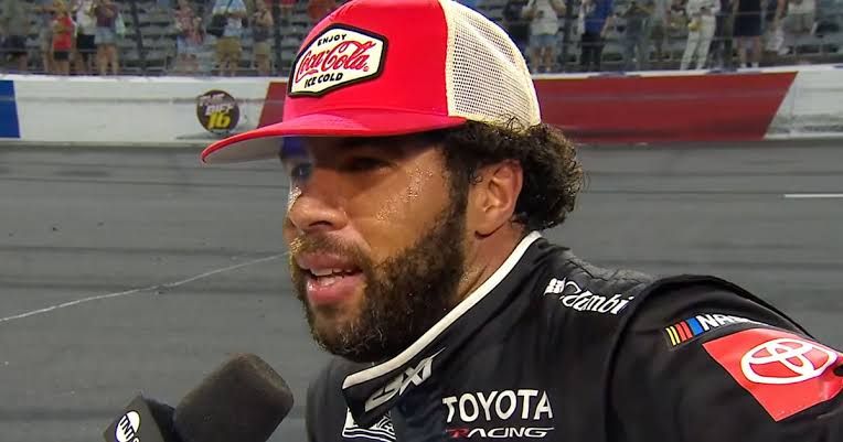 Bubba Wallace standing by his car at the Window World 450 race track.