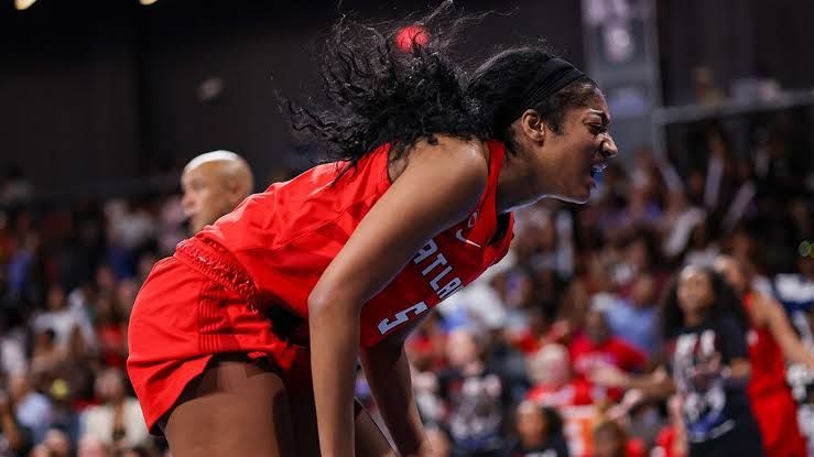 Angel Reese sitting on the court holding her leg after an injury during the Atlanta Dream game against the Chicago Sky.