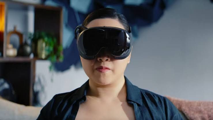 A woman wearing the Steam Frame virtual reality headset in a promotional studio setting.
