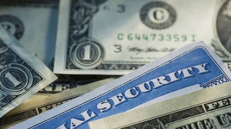 Close up of an official Social Security Administration envelope and documents on a wooden desk.