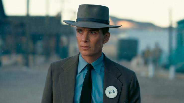 J. Robert Oppenheimer walks down a Los Alamos street wearing his signature hat in a scene from the film Oppenheimer.