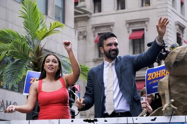 New York City Mayor Zohran Mamdani speaking at a press event while crowds gather in the background.