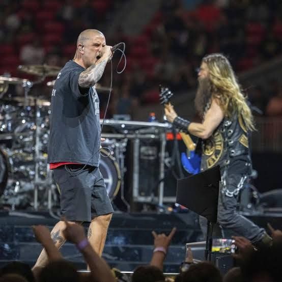 Phil Anselmo performs during a live Pantera concert while holding the microphone stand on stage.