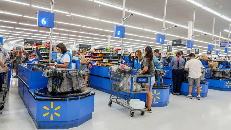 Customers using a mobile phone to pay at a self-checkout station inside a retail store.