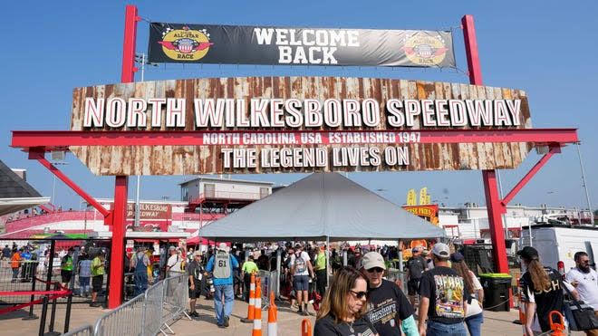 A vintage-style shot of the North Wilkesboro Speedway track with grandstands packed for a weekend race event.