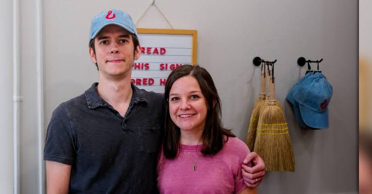 Shane and Lauren Fallon standing inside Red Hook Stationery Co. surrounded by shelves of notebooks and pens.