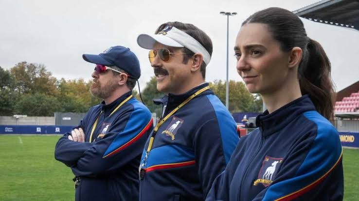 Jason Sudeikis, Brendan Hunt, and Tanya Reynolds on the soccer pitch for season four of the series Ted Lasso.