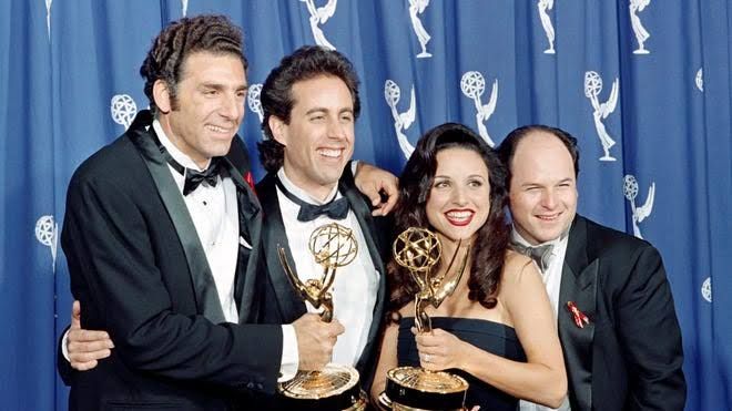 Julia Louis-Dreyfus holding an Emmy award, reflecting on her time on the sitcom Seinfeld.