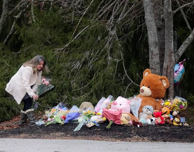 A woman places flowers at a makeshift memorial for the victims of the Lindsay Clancy case in Duxbury.