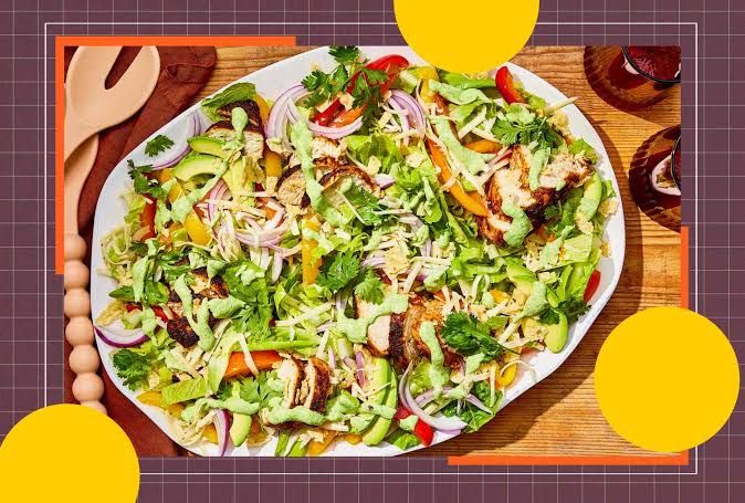 Kelsey Kunik, RDN holding a bowl of Chicken Fajita Salad with fresh vegetables.
