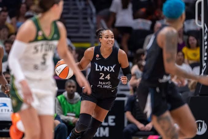 Kelsey Plum dribbling the ball past a defender during a professional basketball game.