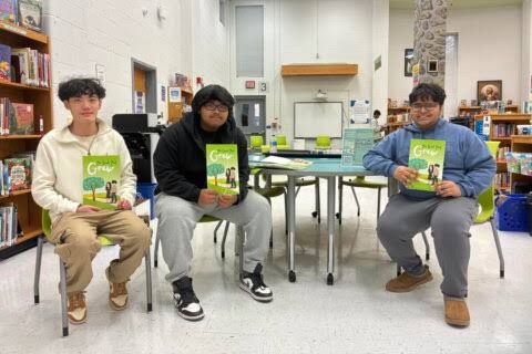 Oakton High School students displaying their financial literacy book The Seed That Grows to a group of elementary students.