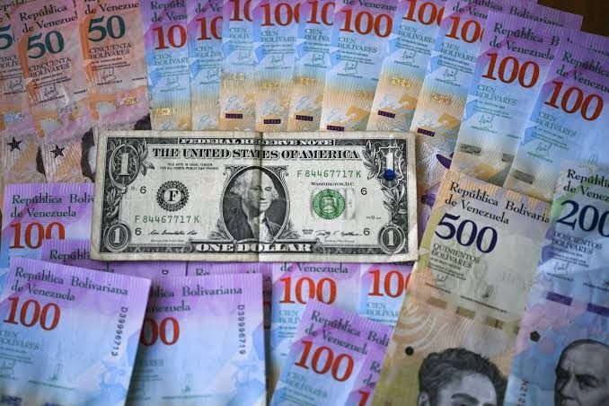 Venezuelan bolivar banknotes and a single US dollar bill on a flat surface in Caracas, symbolizing current currency trends.