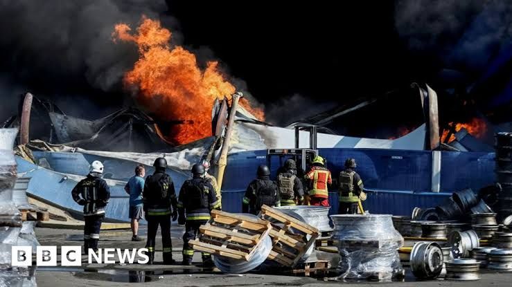 Ukrainian firefighters observe flames rising from the debris of a warehouse following a drone strike near Kyiv.