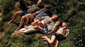 Prince William and Princess Kate with Prince George, Princess Charlotte, and Prince Louis lying in the grass.