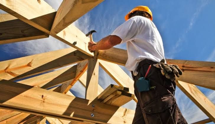 New construction houses with wooden frames under a blue sky during a sunny day.
