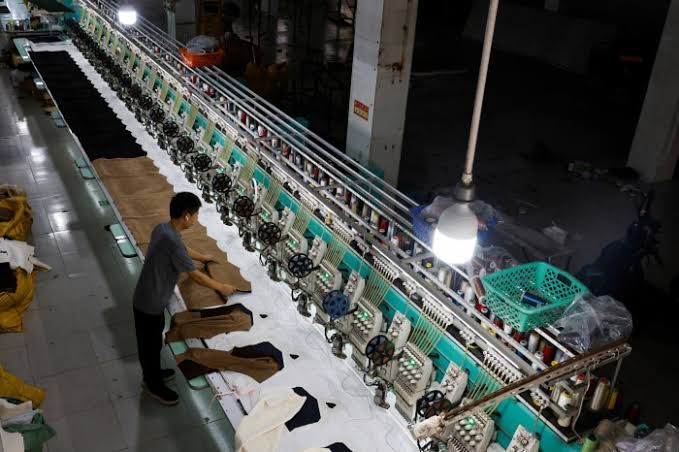 A bustling factory floor in China with automated assembly lines showing heavy machinery and workers managing production.