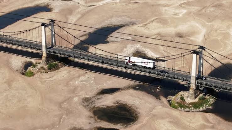 A dried riverbed in France during the 2026 drought with cracked earth and exposed stones where water should be flowing.